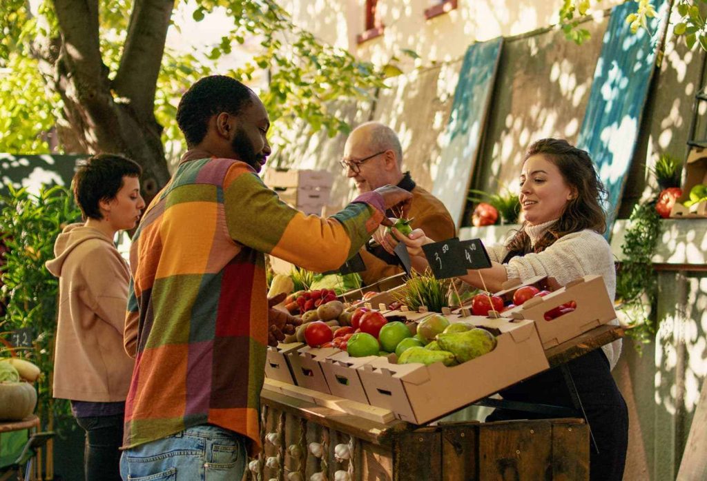 Woman at a farmers market selling apples to a man