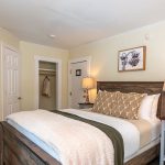 Queen bed with nightstand and plant in Standard 1 Queen Room