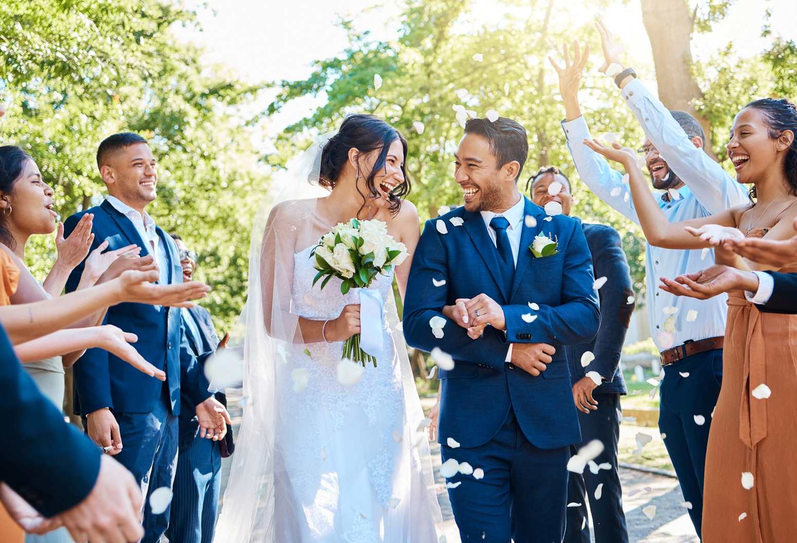 Wedding guests throwing rose petals over bride and groom in Vermont