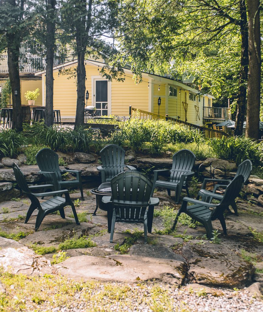 Firepit with chairs around it. Lodge in background during daytime
